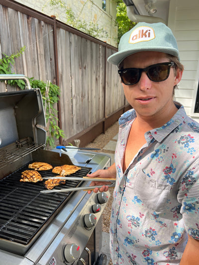 man barbecues while wearing alki supply light blue snapback corduroy hat